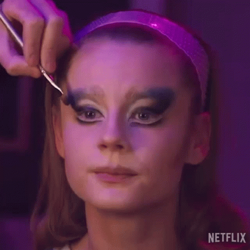 a woman is getting her makeup done by a makeup artist with a brush .
