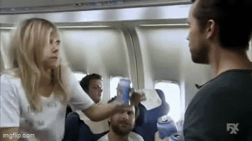 A Woman Is Giving A Man A Beer On An Airplane . GIF