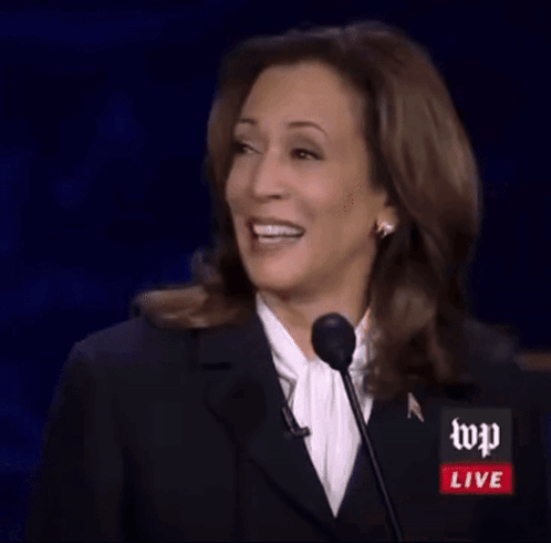 A Woman Is Giving A Speech In Front Of A Microphone With Wp Live Written On It GIF
