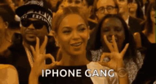 A Woman Is Giving An Ok Sign In Front Of A Crowd Of People With The Words Iphone Gang Written Below Her GIF