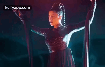 A Woman Is Hanging From A Rope In A Dark Room . GIF