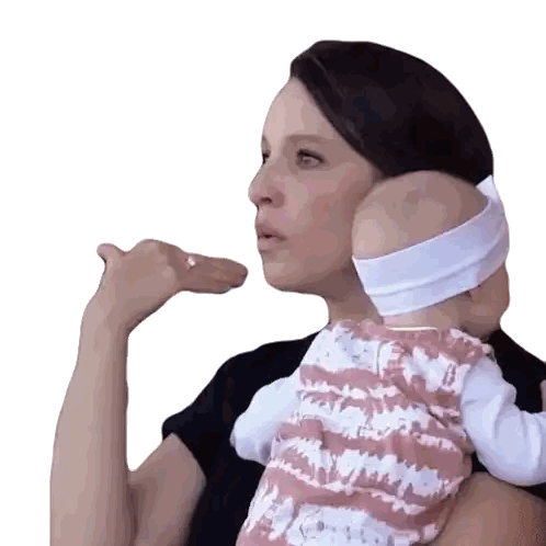 a woman is holding a baby in her arms and making a gesture with her hand