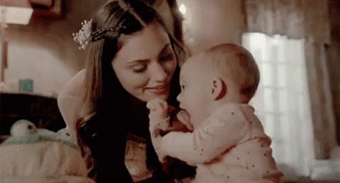A Woman Is Holding A Baby In Her Arms In A Bedroom . GIF