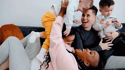 A Woman Is Holding A Baby In Her Arms While Another Woman Holds A Baby In Her Lap GIF