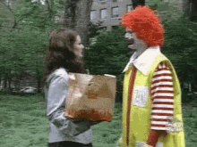 A Woman Is Holding A Bag Of Mcdonald 'S French Fries And Talking To A Clown . GIF