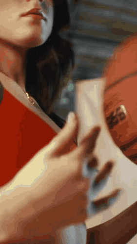 A Woman Is Holding A Book And A Basketball GIF