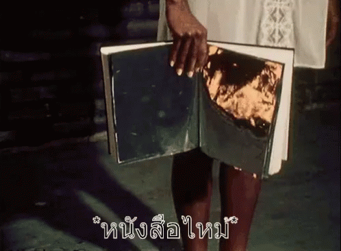 A Woman Is Holding A Book With A Piece Of Gold Foil On It . GIF