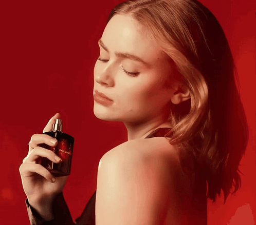 A Woman Is Holding A Bottle Of Perfume That Says Yves Saint Laurent On It GIF