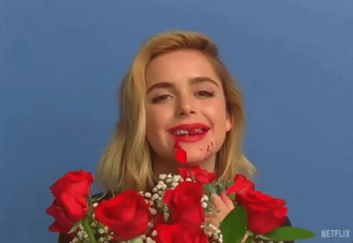 A Woman Is Holding A Bouquet Of Red Roses And Has Blood On Her Face . GIF