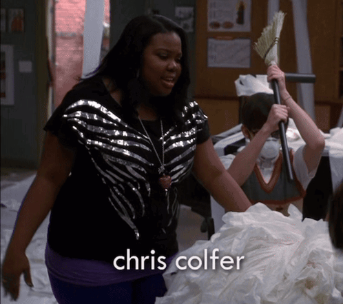 A Woman Is Holding A Broom And The Name Chris Colfer Is On The Bottom GIF