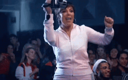 A Woman Is Holding A Camera In Front Of A Crowd Of People . GIF