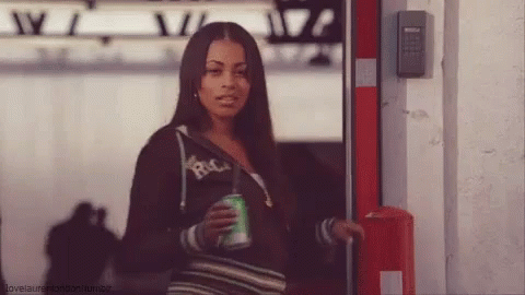 A Woman Is Holding A Can Of Soda And Wearing A Hoodie That Says Rica GIF