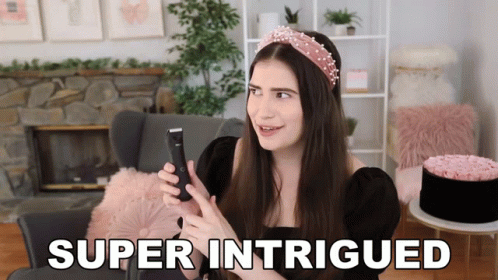 A Woman Is Holding A Cell Phone And The Words Super Intrigued Are On The Screen GIF