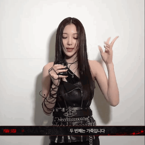 A Woman Is Holding A Cell Phone In Front Of A Sign That Says Yin Seo GIF