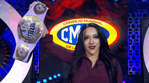 A Woman Is Holding A Championship Belt In Front Of A Cm Logo . GIF