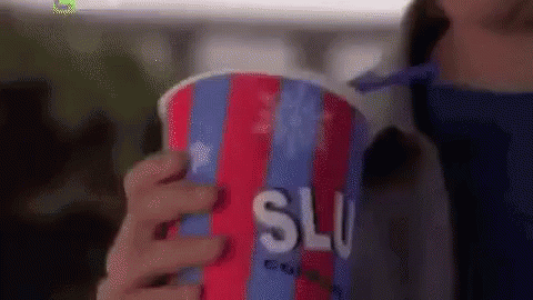 A Woman Is Holding A Colorful Cup Of Slushy Ice Cream . GIF