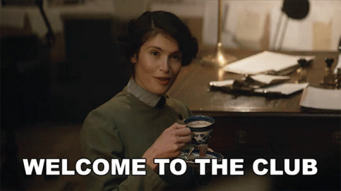 A Woman Is Holding A Cup Of Tea With The Words Welcome To The Club Behind Her GIF