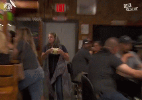 a woman is holding a drink in front of a bar rescue sign