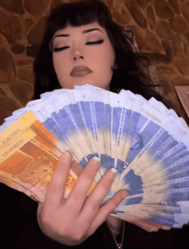 A Woman Is Holding A Fan Of Money That Says ' Switzerland ' On The Front GIF