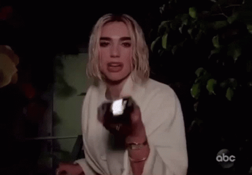 A Woman Is Holding A Flashlight In Her Hand And Looking At The Camera . GIF