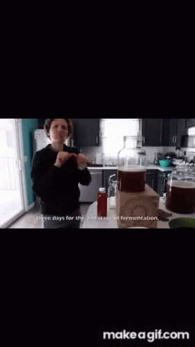 A Woman Is Holding A Glass In A Kitchen And Says This Is For The Flavor To Really Soak In .. GIF