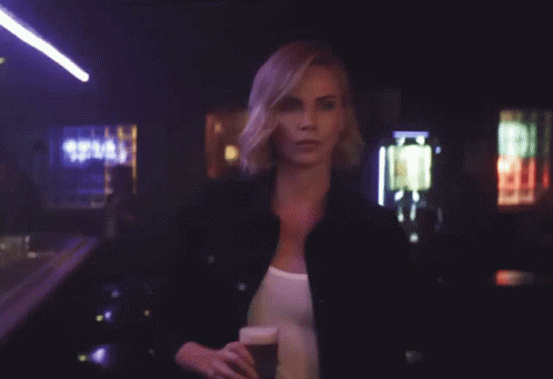 A Woman Is Holding A Glass Of Beer With The Words Hold My Beer Behind Her GIF