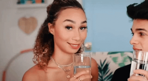 A Woman Is Holding A Glass Of Water Next To A Man Holding A Glass Of Water . GIF