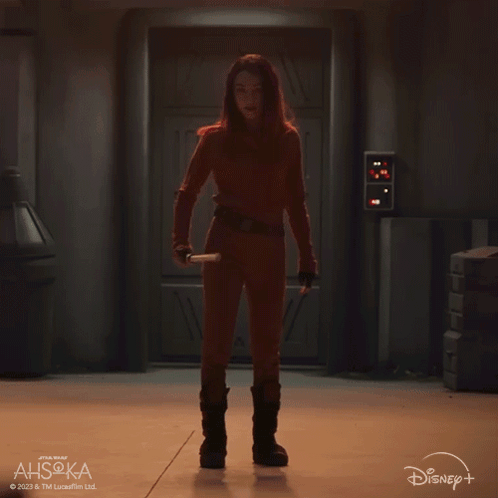 A Woman Is Holding A Green Lightsaber In Front Of A Disney Logo GIF