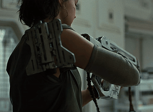 A Woman Is Holding A Gun With The Letter X On The Back GIF