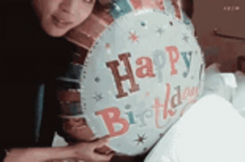 A Woman Is Holding A Happy Birthday Balloon In Her Hands . GIF