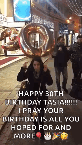 A Woman Is Holding A Large Balloon In The Shape Of A Number 30 . GIF