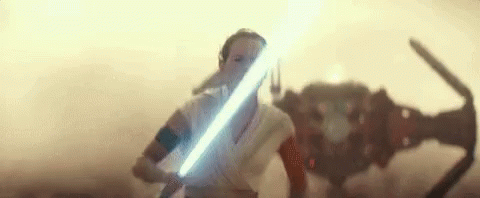 A Woman Is Holding A Light Saber In Front Of A Robot In A Star Wars Movie . GIF