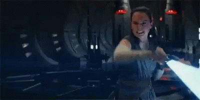 A Woman Is Holding A Light Saber In Her Hand In A Dark Room In A Star Wars Movie . GIF