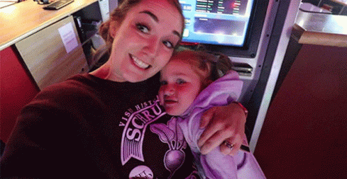 A Woman Is Holding A Little Girl Who Is Wearing A Shirt That Says ' Visit Histo ' On It GIF