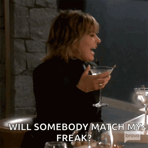 A Woman Is Holding A Martini Glass And Saying " Will Somebody Match My Freak ? " GIF