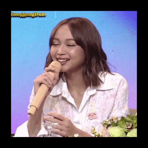 A Woman Is Holding A Microphone And Smiling In Front Of A Screen That Says Linggang Dulo GIF