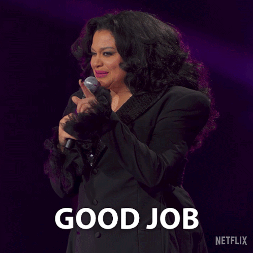 A Woman Is Holding A Microphone In Front Of A Sign That Says Good Job On It GIF