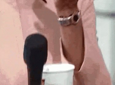 A Woman Is Holding A Microphone In Front Of Her Face . GIF