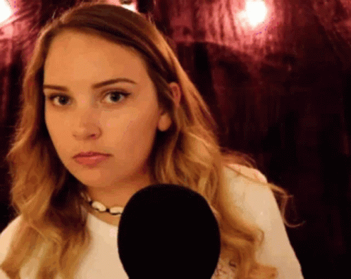 A Woman Is Holding A Microphone In Front Of Her Face And Making A Funny Face GIF