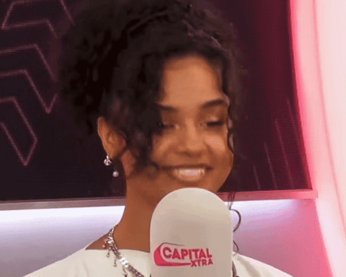 A Woman Is Holding A Microphone That Says Capital Xtra On It GIF