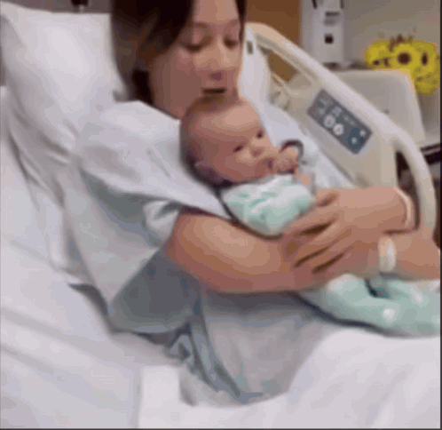 a woman is holding a newborn baby in a hospital bed .