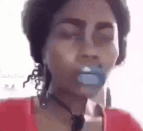 A Woman Is Holding A Pacifier In Her Mouth While Wearing A Red Shirt . GIF