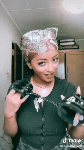 A Woman Is Holding A Pair Of Handcuffs In Her Hands . GIF