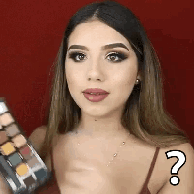 A Woman Is Holding A Palette Of Eye Shadows And Has A Question Mark On Her Arm . GIF