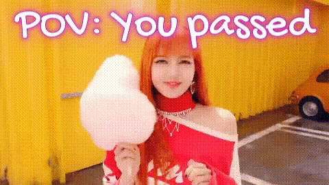A Woman Is Holding A Piece Of Cotton Candy In Front Of A Yellow Building . GIF