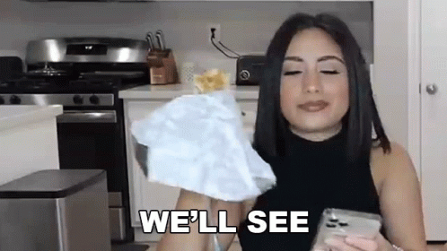 A Woman Is Holding A Piece Of Paper And Saying `` We 'Ll See '' While Standing In A Kitchen . GIF