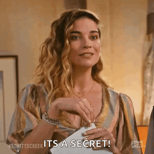 a woman is holding a piece of paper in her hand and saying it 's a secret .