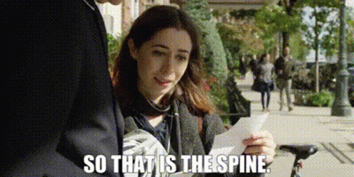 A Woman Is Holding A Piece Of Paper In Her Hand While Standing Next To A Man On A Sidewalk . GIF