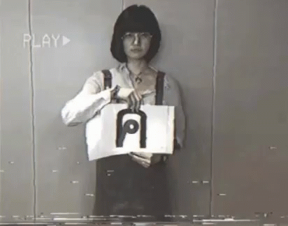 A Woman Is Holding A Piece Of Paper With The Letter A On It GIF