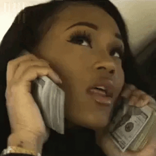 A Woman Is Holding A Pile Of Money And Talking On A Cell Phone . GIF